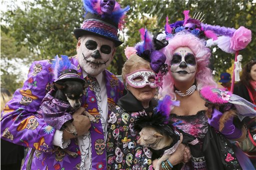 Danny Cox, left, with his Chihuahua Paco, Alice Woodroof, center, with her Chihuahua Pearl and Amy Cox with her Yorkshire Terrier Penelope, all from Dallas, Texas, wear Day of the Dead costumes in the annual Tompkins Square Halloween Dog Parade in New York on Saturday, Oct. 24, 2015. Hundreds of dogs took part in what's billed as the nation's largest Halloween dog parade. (AP Photo/Mary Altaffer)