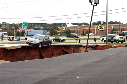 A car teeters on the edge of a cave-in of a parking lot in Meridian, Miss., Sunday, Nov. 8, 2015. Experts are to begin work Monday seeking to determine the cause of the Saturday collapse, authorities said. (Michael Stewart/The Meridian Star via AP) MANDATORY CREDIT