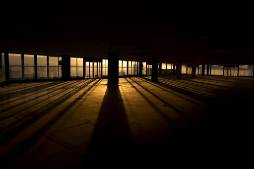 In this photo taken on Thursday, July 16, 2015, the sun lights the former international terminal at the abandoned old Athens International Airport, which shut down in 2001. The property, along with idling installations built for the Athens 2004 Olympics, is Greece's most valuable piece of real estate whose sale has been mired in controversy. (AP Photo/Petros Giannakouris)