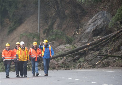 Washington Gov. Jay Inslee, right,  is briefed by department of transportation officials as they survey the scene of a mudslide obstructing the northbound lane of Interstate 5 near Woodland,, Was., Thursday, Dec. 10, 2015. Boulders, trees and dirt slid onto the highway in the day before following heavy rains. (Natalie Behring/The Columbian via AP) MANDATORY CREDIT