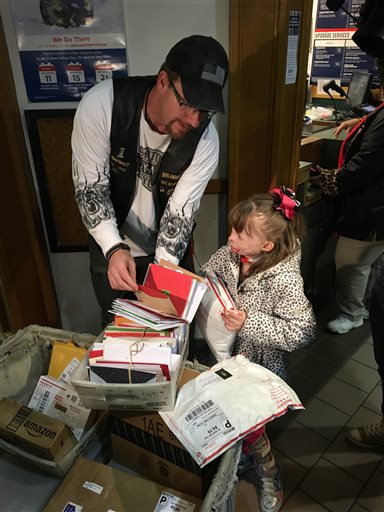 Safyre Terry, 8, and Kevin Clark collect cards and gifts on Wednesday, Dec. 9, 2015, at a post office near her home in Rotterdam, N.Y. Terry, who lost her father and three younger siblings and was burned over 75 percent of her body in a May 2013 house fire, has been receiving cards from across the country since her custodial aunt posted a Facebook photo of her saying she wants cards for a Christmas tree display stand. Clark, a member of a motorcycle club that participated in a benefit for Safyre this fall, shared the original post and said it has been shared tens of thousands of times all over the world. A crowd funding site has generated more than $177,000 for the family. (AP Photo/Mary Esch)