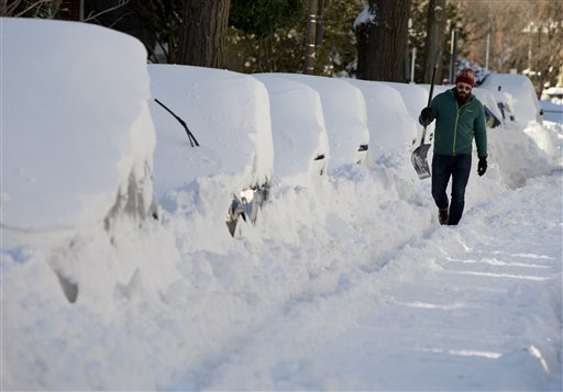 Ben Osborn walks with a shovel past a line of snowed-in cars A Steet in northeast Washington, Sunday, Jan. 24, 2016. Washington is digging out after a mammoth blizzard with hurricane-force winds and record-setting snowfall brought much of the East Coast to an icy standstill. (AP Photo/Carolyn Kaster)