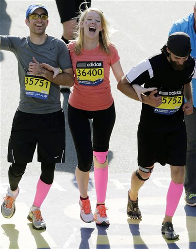 FILE - In this April 21, 2014 file photo, Timothy Haslet, left, and David Haslet, right, celebrate with their sister Adrianne Haslet-Davis at the finish line of the 118th Boston Marathon, after she completed a short distance of the course in Boston. Haslet-Davis said she is training to run the entire Boston Marathon on Monday, April 18, 2016. Haslet-Davis lost her left leg below the knee in the April 2013 bombing attacks, which killed three people and wounded more than 260 others. (AP Photo/Charles Krupa, File)