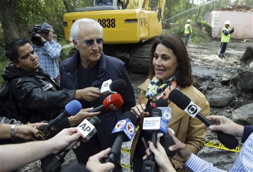 Chicken Kitchen restaurant owner Christian de Berdouare, left, and his wife Jennifer Valoppi, right, talk with the media outside of the waterfront mansion formerly owned by Colombian drug lord Pablo Escobar, Tuesday, Jan. 19, 2016, in Miami Beach, Fla. The couple, who purchased the property in 2014, want to build a more modern home on the site. Before demolishing the fire-damaged mansion that sat abandoned for years, de Berdouare hired professional treasure hunters to comb through the structure for traces from Escobar's days. (AP Photo/Lynne Sladky)