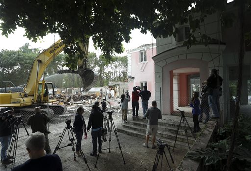 An excavator demolishes the waterfront mansion formerly owned by Colombian drug lord Pablo Escobar, Tuesday, Jan. 19, 2016, in Miami Beach, Fla. Chicken Kitchen owner Christian de Berdouare, who purchased the property in 2014, wants to build a more modern home on the site. Before demolishing the fire-damaged mansion that sat abandoned for years, de Berdouare hired professional treasure hunters to comb through the structure for traces from Escobar's days. (AP Photo/Lynne Sladky)