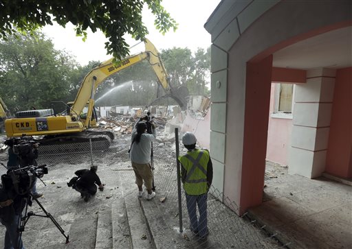 An excavator demolishes the waterfront mansion formerly owned by Colombian drug lord Pablo Escobar, Tuesday, Jan. 19, 2016, in Miami Beach, Fla. Chicken Kitchen owner Christian de Berdouare, who purchased the property in 2014, wants to build a more modern home on the site. Before demolishing the fire-damaged mansion that sat abandoned for years, de Berdouare hired professional treasure hunters to comb through the structure for traces from Escobar's days. (AP Photo/Lynne Sladky)