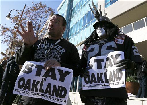 Oakland Raiders fans Griz Jones, left, and Ray Perez make their case for keeping the NFL football team in Oakland outside the hotel where NFL owners are meeting Tuesday, Jan. 12, 2016, in Houston to discuss possible relocation to Los Angeles. (AP Photo/Pat Sullivan)