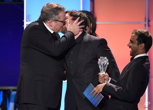 Adam McKay, left, kisses Christian Bale as he accepts the award for best comedy for "The Big Short" at the 21st annual Critics' Choice Awards at the Barker Hangar on Sunday, Jan. 17, 2016, in Santa Monica, Calif. Presenter Aziz Ansari laughs on right (Photo by Chris Pizzello/Invision/AP)
