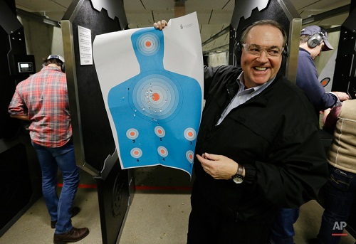 Republican presidential candidate, former Arkansas Gov. Mike Huckabee, shows off a target during a campaign stop at the Crossroads Shooting Sports, Saturday, Jan. 30, 2016 in Johnston, Iowa. (AP Photo/Chris Carlson)