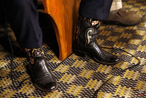 Wearing Western boots with Florida state flags emblazoned on them, Republican presidential candidate, former Florida Gov. Jeb Bush sits on a bench as he waits to be introduced before speaking at a campaign stop, Wednesday, Jan. 13, 2016, at The Machine Shed restaurant in Urbandale, Iowa. (AP Photo/Patrick Semansky)
