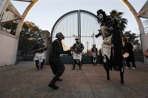 Members of the North Side Skull & Bone Gang dance in front of the Louis Armstrong park during the wake up call for Mardi Gras, Tuesday, Feb. 9, 2016, in New Orleans. Their costumes are intended to represent the dead and they bring a serious message, reminding people of their mortality and the need to live a productive and good life. (AP Photo/Brynn Anderson)