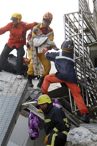 A child is rescued from a toppled building after a 6.4-magnitude earthquake in Tainan, Taiwan, Saturday, Feb. 6, 2016. The earthquake struck southern Taiwan early Saturday, toppling at least one high-rise residential building and trapping people inside. (AP Photo) TAIWAN OUT