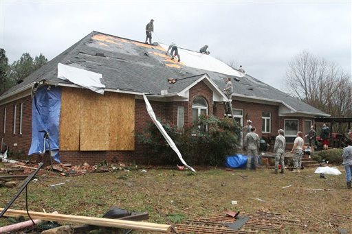 Friends and neighbors work on the roof of the home of Debbie McCormick on Shelby Road near Newton, Miss., that received extensive damage after a storm Tuesday, Feb. 2, 2016. A tornado damaged homes and at least one church, and strong winds damaged student housing at a community college Tuesday in eastern Mississippi. Authorities said no injuries were immediately reported. (Robbie Robertson/The Newton County Appeal via AP)