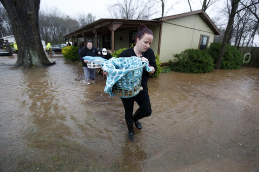 Camie Kelly walks through floodwaters as she carries her family cat from the the Pecan Valley Estates trailer park as residents evacuate due to rising water in Bossier City, La., Wednesday, March 9, 2016. (AP Photo/Gerald Herbert)