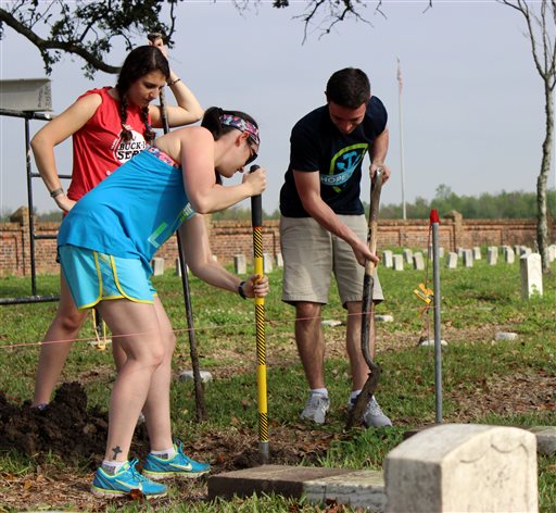 ADDS NAMES OF STUDENTS - In a Wednesday, March 16, 2016 photo, Ohio State University students Sivan Zouela, back left, Jill Auxter and Ryan Seybold work to straighten a gravestone at Chalmette Natinoal Cemeterywork in Chalmette, La. They were among about 50 Ohio State students working at the cemetery on Wednesday, March 16, 2016, as part of a nearly month-long project organized by the National Trust for Historic Preservation. (AP Photo/Janet McConnaughey)