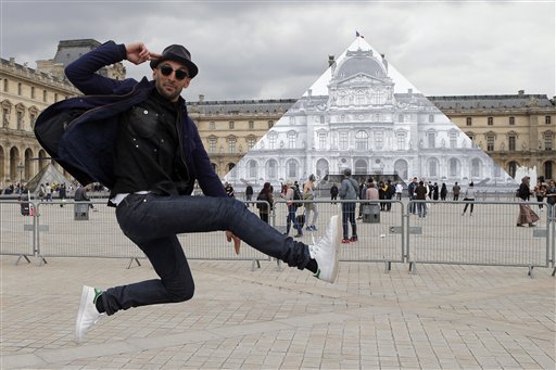 Street artist JR poses in front the Louvre Pyramid in Paris, Tuesday, May 24, 2016. For his latest bold project, street artist JR is creating an eye-tricking installation at the Louvre Museum that makes it seem as if the huge glass pyramid at the heart of the courtyard has disappeared. (AP Photo/Francois Mori)