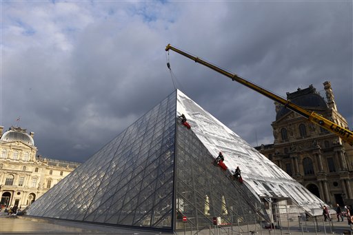 Rope access technicians paste a giant picture on the Louvre Pyramid as part of JR project in Paris, Monday, May 23, 2016. For his latest bold project, street artist JR is creating an eye-tricking installation at the Louvre Museum that makes it seem as if the huge glass pyramid at the heart of the courtyard has disappeared. (AP Photo/Francois Mori)