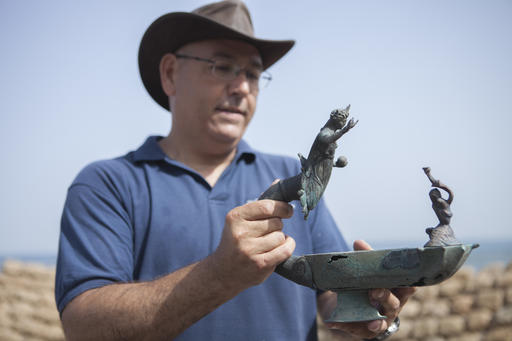 Jacob Sharvit, director of the Marine Archaeology Unit of the Israel Antiquities Authority, holds a bronze lamp depicting the image of a Roman sun god Sol Invictus, in Cesarea, Israel, Monday, May 16, 2016. Israeli archeologists say two divers have made the country's biggest discovery of Roman-era artifacts in three decades. (AP Photo/Dan Balilty)