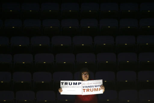 A supporter is illuminated by lights as she holds signs for Republican presidential candidate Donald Trump during a rally at the Anaheim Convention Center, Wednesday, May 25, 2016, in Anaheim, Calif. (AP Photo/Jae C. Hong)
