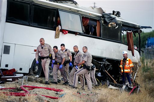 California Highway Patrol officers investigate the scene of a charter bus crash on northbound Highway 99 between Atwater and Livingston, Calif., Tuesday, Aug. 2, 2016. The bus veered off the central California freeway before dawn Tuesday and struck a pole that sliced the vehicle nearly in half, authorities said. (Andrew Kuhn/Merced Sun-Star via AP)