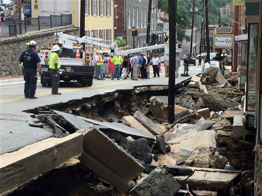 Workers gather by street damage after Saturday night's flooding in Ellicott City, Md., Sunday, July 31, 2016. Historic, low-lying Ellicott City, Maryland, was ravaged by floodwaters Saturday night, killing a few people and causing devastating damage to homes and businesses, officials said. (Kevin Rector/The Baltimore Sun via AP)
