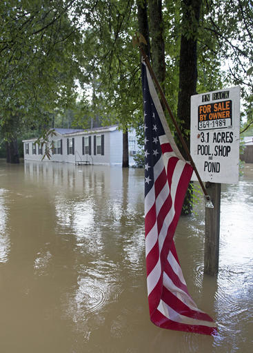 An American flag hangs in the water next to a for sale sign in flood waters in Walker, La., Monday, Aug. 15, 2016. Flood waters continued to cause problems throughout the area. (AP Photo/Max Becherer)