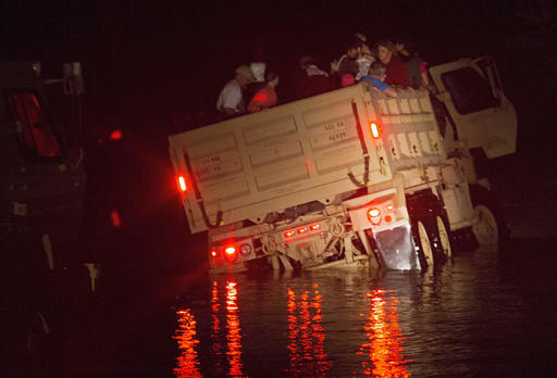In this Sunday, Aug. 14, 2016 photo, a Louisiana Army National Guard dump truck loaded with flood victims tilts after driving slightly off the road after rescuing people from the Hebron Baptist Church in Denham Springs, La. The truck was able to back up and continue to safety. About 200 people were taken to the church by the fire department on Friday and Saturday then became stranded as flood waters continued to rise. (AP Photo/Max Becherer)