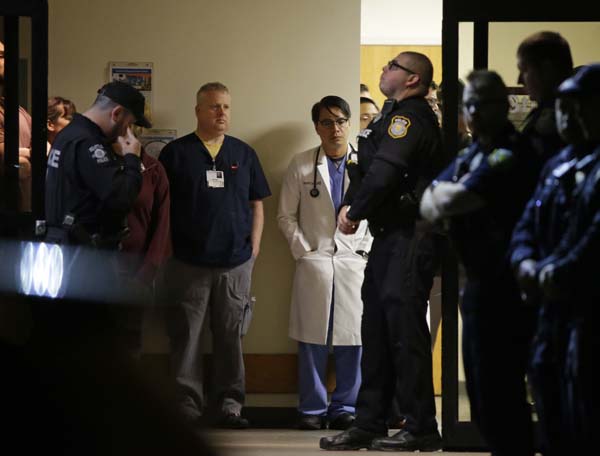 Hospital and law enforcement workers stand at an entrance to Tacoma General Hospital in Tacoma, Wash., as they wait for the body of a Tacoma Police officer who was shot and killed while answering a domestic violence call Wednesday, Nov. 30, 2016, to be removed from the hospital in a procession, in Tacoma, Wash. Tacoma Police spokeswoman Loretta Cool said the officer was pronounced dead at the hospital Wednesday evening. "We've suffered a great loss and I think the community has suffered a great loss. I don't know how to put that into words," Cool said. (AP Photo/Ted S. Warren)