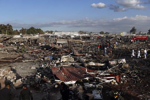 Firefighters and rescue workers walk through the scorched ground of the open-air San Pablito fireworks market, in Tultepec, outskirts of Mexico City, Mexico, Tuesday, Dec. 20, 2016.  An explosion ripped through Mexico’s best-known fireworks market on the northern outskirts of the capital Tuesday, injuring scores and killing dozens, according to Mexican Federal Police. (AP Photo/Eduardo Verdugo)